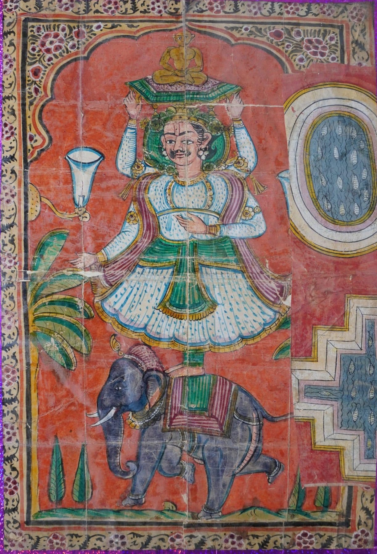 A painted panel of a crowned, many-armed figure seated above an elephant, on an orange ground.