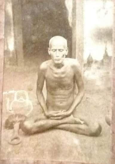 A worn sepia print of the Acharya seated cross-legged in meditation, outdoors.