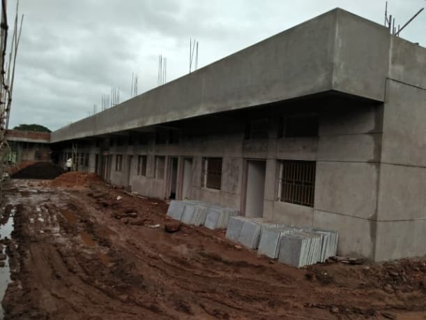 A long concrete building, its walls still unpainted, during the works.