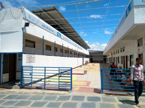 The completed Samudaya Bhavan at Yarnal: long, whitewashed wings with blue railings around a paved courtyard.