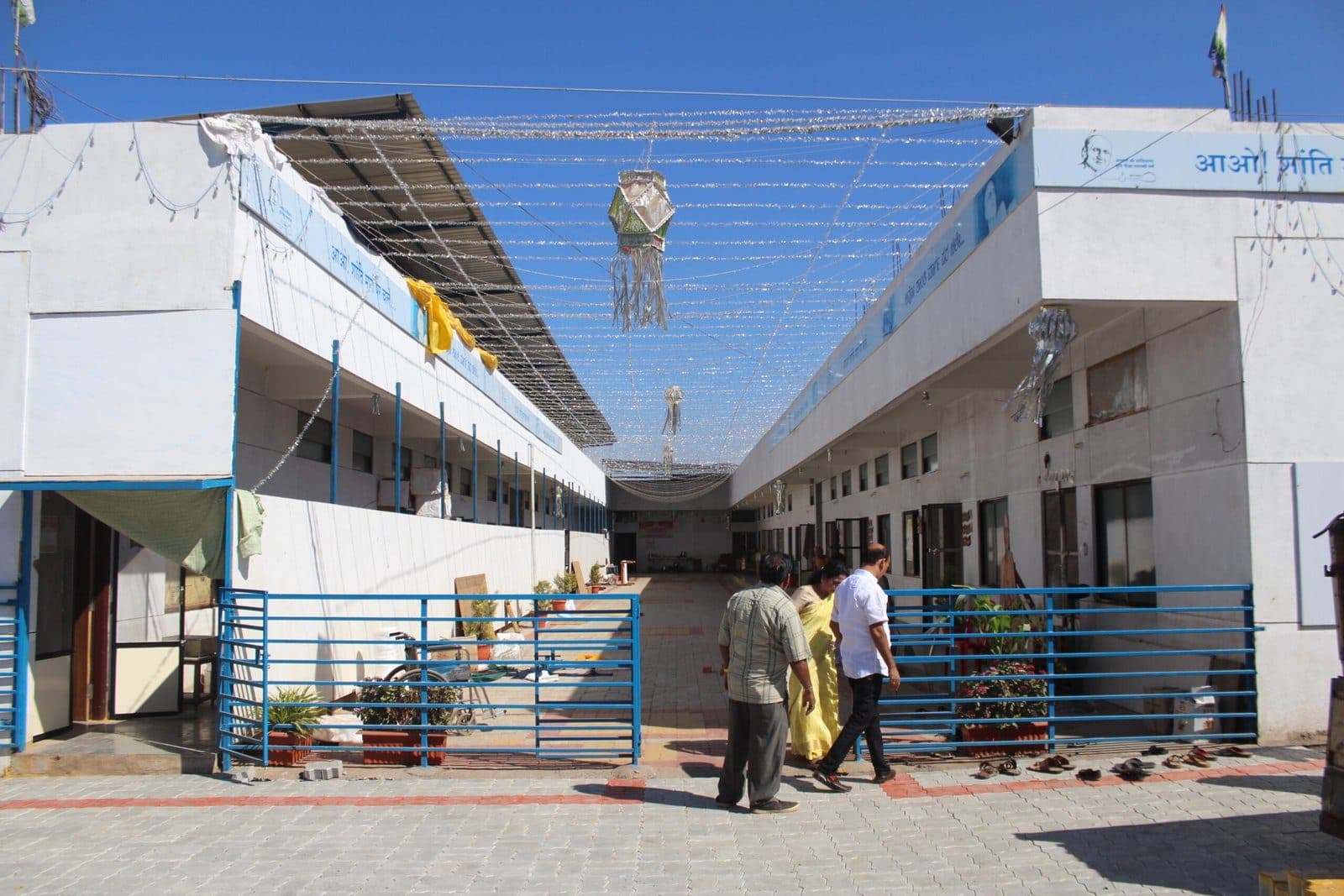 The completed Samudaya Bhavan at Yarnal: long whitewashed wings with blue railings around a paved courtyard.