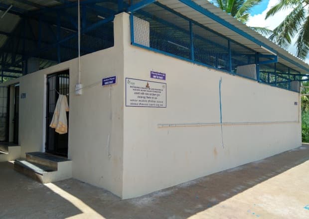 A whitewashed toilet block with signboards on its wall.