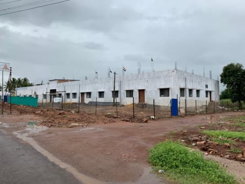 A long, whitewashed single-storey building behind a fence.