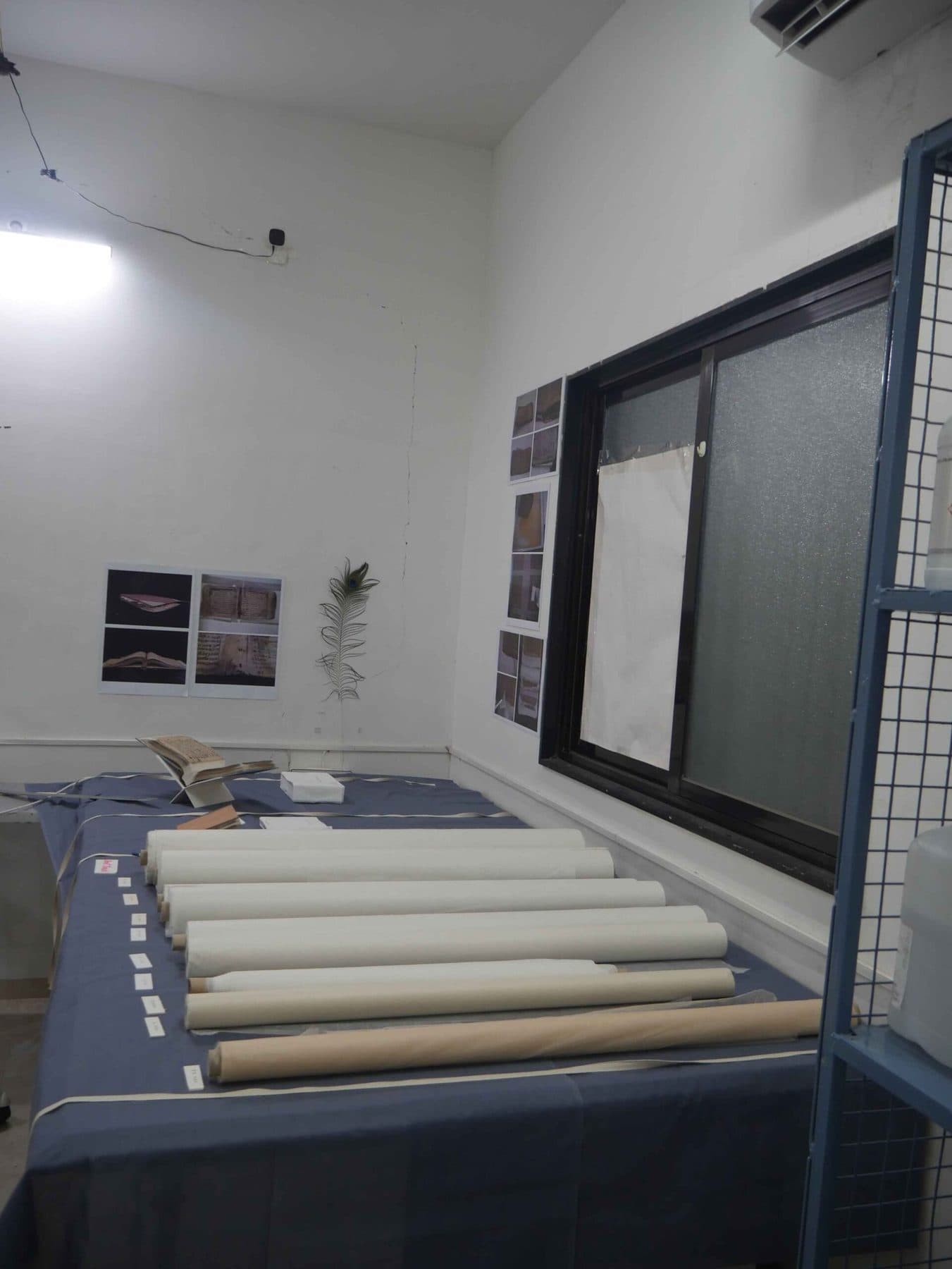 Rolls of paper laid on a blue cloth in a bright conservation room.